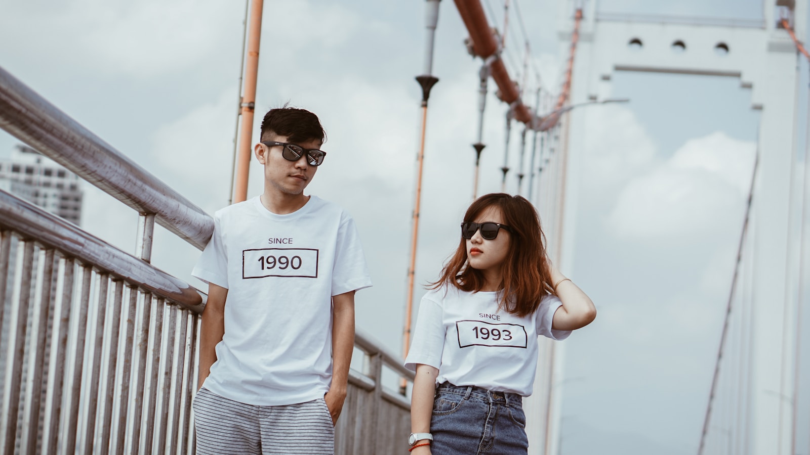 man and woman standing beside gray rails on bridge during daytime