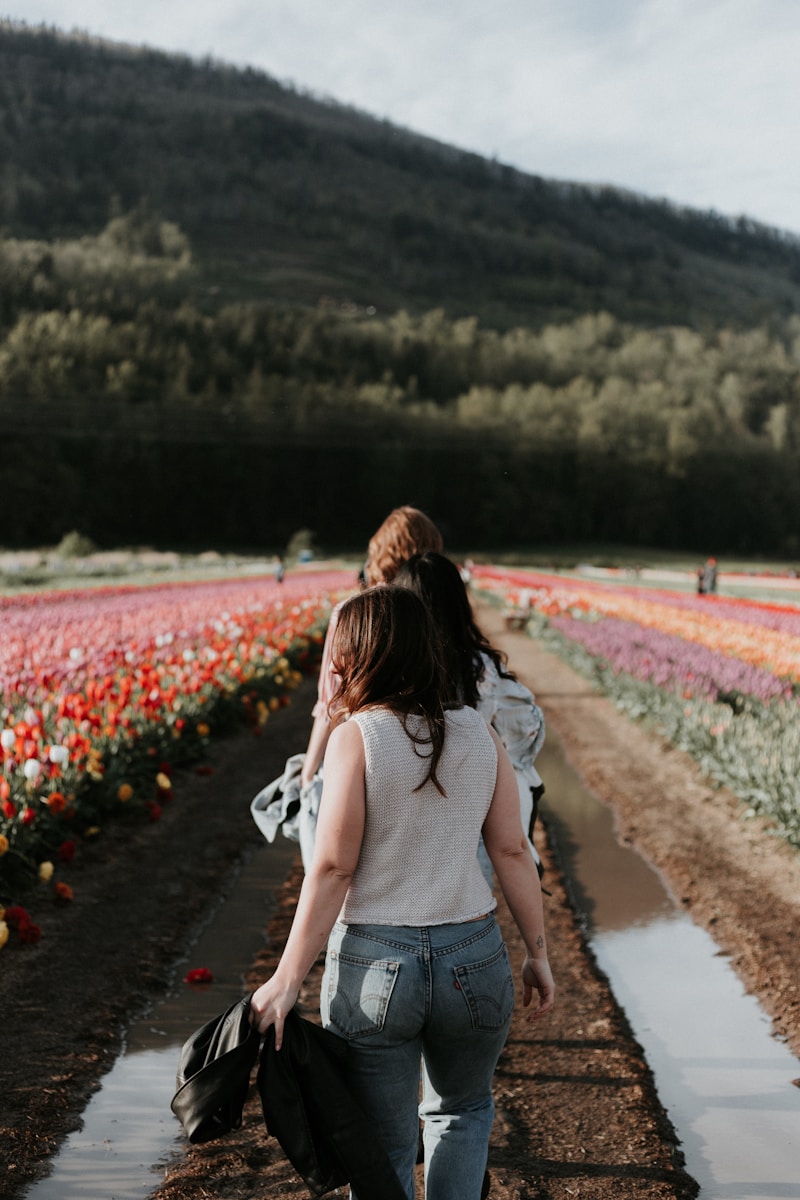 two girl walking near flower field during daytime